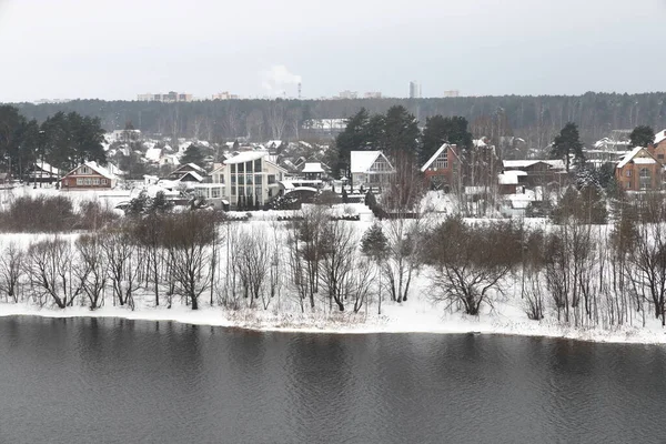 Güneşli bir akşamda nehir. Ağaçlar ve çalılar. Kış manzarası, nehir kıyıları çalılarla kaplı.