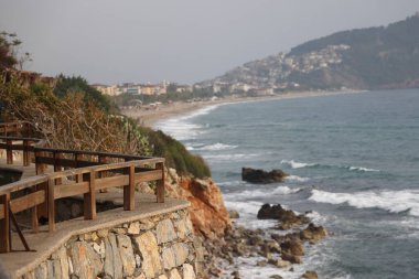 Kleopatra Sahili 'nde fırtına, köpük dalgaları, uçurumun üzerindeki sahil kafesi tarihi dağ Alanya' nın arka planında tahta çit, Kasım 2021