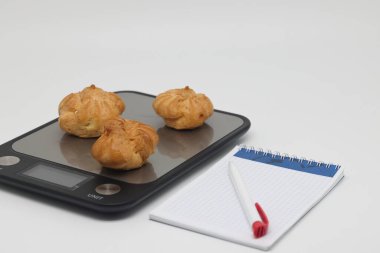 Kremalı kekler ve pastalar elektronik mutfak tartıları, kalori sayımı ve ağırlık kontrolü, ekstra kalori ve diyet ihlali üzerine uzanır.