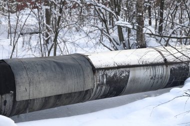 Ana su şehire sıcak su sağlıyor. Boru hattının gövdesi. Seçici odaklanma. Merkezi ısıtma sisteminin büyük boruları karla kaplıdır. Borulardaki buz saçakları. Yakıt krizi. Isıtma maliyetinin artırılması