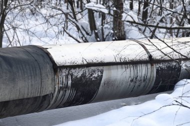 Ana su şehire sıcak su sağlıyor. Boru hattının gövdesi. Seçici odaklanma. Merkezi ısıtma sisteminin büyük boruları karla kaplıdır. Borulardaki buz saçakları. Yakıt krizi. Isıtma maliyetinin artırılması