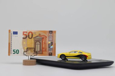 A toy car stands on an electronic scale next to a stand with a banknote, the concept of determining the cost of a car when selling, car insurance and car loans clipart