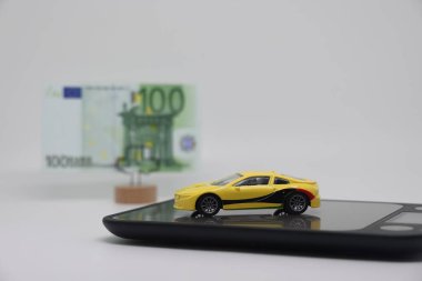 Oyuncak bir araba, satılırken arabanın fiyatını, araba sigortasını ve araba kredilerini belirleme kavramı, banknotu olan bir standın yanında elektronik ölçekte duruyor.