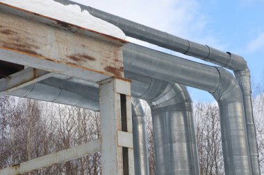 Ana su şehire sıcak su sağlıyor. Seçici odaklanma. Merkezi ısıtma sisteminin büyük boruları karla kaplıdır. Borulardaki buz saçakları. Yakıt krizi. Isıtma maliyetinin artırılması