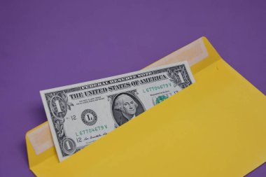 Banknotlar mor arka planda sarı bir zarfın içinde. Rüşvet konsepti. Maaşlar zarflarda. Finansal dolandırıcılık. Kapat.
