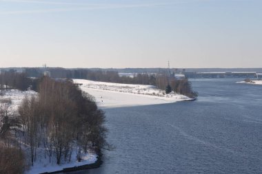 Güneşli bir günde nehir. Ağaçlar ve çalılar. Kış manzarası, nehir kıyıları çalılarla kaplı.
