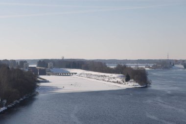 Güneşli bir günde nehir. Ağaçlar ve çalılar. Kış manzarası, nehir kıyıları çalılarla kaplı.