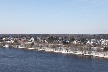 Güneşli bir günde nehir. Ağaçlar ve çalılar. Kış manzarası, nehir kıyıları çalılarla kaplı.