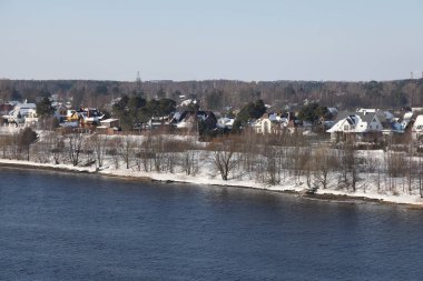 Güneşli bir günde nehir. Ağaçlar ve çalılar. Kış manzarası, nehir kıyıları çalılarla kaplı.