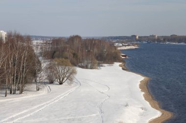 Güneşli bir günde nehir. Ağaçlar ve çalılar. Kış manzarası, nehir kıyıları çalılarla kaplı.