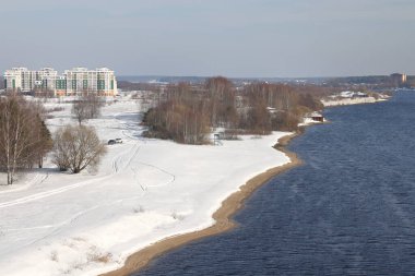 Güneşli bir günde nehir. Ağaçlar ve çalılar. Kış manzarası, nehir kıyıları çalılarla kaplı.
