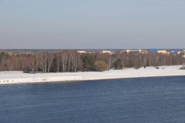 Güneşli bir günde nehir. Ağaçlar ve çalılar. Kış manzarası, nehir kıyıları çalılarla kaplı.