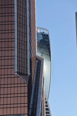 Gökdelenlerin geleceksel tasarımı açık mavi gökyüzüne karşı. Soyut cephe tasarımı. Modern şehir mimarisinde cam ve metal. Modern binaların dış görünüşü. Soyutlama. Geometri