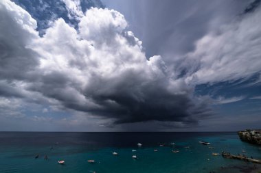 Curacao ve Karayipler 'in etrafındaki turkuaz denizin üzerinde uçan bulutlarla dolu sağanak manzarası.