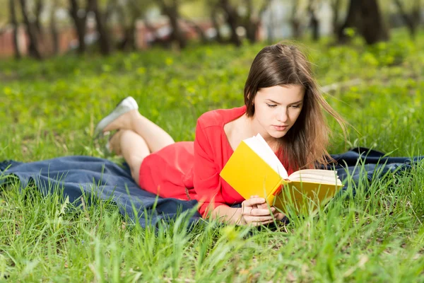 Schönes junges Mädchen liest Buch im Park — Stockfoto