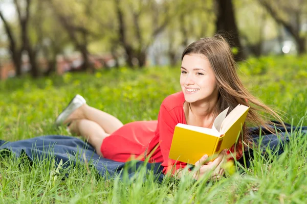 Schönes junges Mädchen liest Buch im Park — Stockfoto