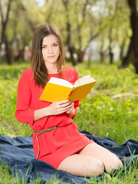 Όμορφη νεαρή κοπέλα διαβάζει το βιβλίο στο πάρκο — Φωτογραφία Αρχείου
