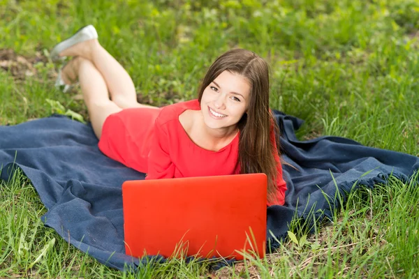 Vacker ung flicka med en bärbar dator i park — Stockfoto
