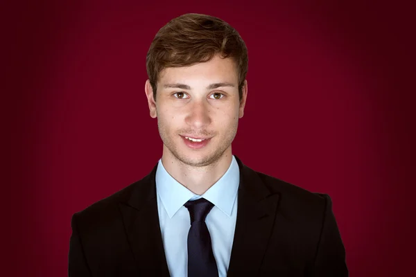 Портрет молодого привлекательного бизнесмена на темно-красном фоне — стоковое фото