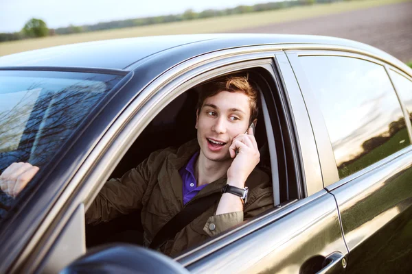 Jonge knappe man rijden auto en spreken op mobiele telefoon — Stockfoto