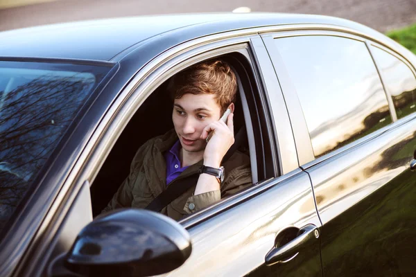 Portret van de jonge knappe man rijden auto en spreekt op mobil — Stockfoto