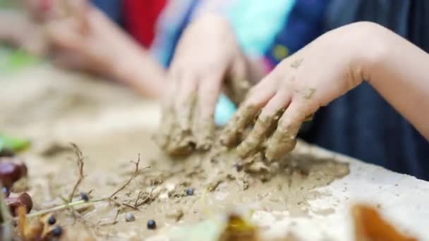 紧紧地握住孩子用粘土雕琢出来的手 创造出秋天树叶的静谧生活 儿童的创造性发展 沼泽地里的手指们正在外面的桌子上玩着游戏艺术 幼儿园 — 图库视频影像