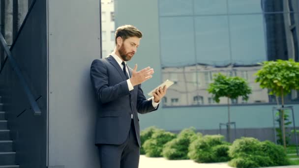 不幸なビジネスマンは デジタルタブレットスマートフォンを使用していらいら感じていた モバイルスパムメッセージに問題がある怒っているビジネスマン 男性のユーザーは 外部の低バッテリまたは悪い信号オフィスに不満 — ストック動画
