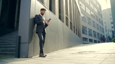 Beyaz sakallı, şehir merkezindeki ofis binasında çalışan, mesajlaşan, iyi haber cep telefonu okuyan. Dışarı çıkın. İş adamı açık havada akıllı telefon kullanarak resmi bir takım elbiseyle mesajlaşıyor.
