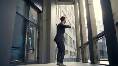 Başarılı Kafkasyalı işadamı kollarını kaldırıp zaferi kutluyor. Kavram: başarı, kariyer gelişimi, zafer, özgürlük. Modern bir ofis binasının arka planında çalışan siluet işadamı. dışarıName