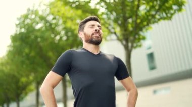 Portre mutlu bir adam doğada duruyor rahatlıyor, temiz hava soluyor gözlerini kapatıyor koşudan ya da şehir parkında antrenmandan sonra erkeğin keyfini çıkarıyor. Akıllı saat fitness takip bilekliği arıyor ve kullanıyor