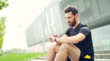 Modern hipodrom koşucusunda akıllı görünümlü beyaz bir adam. Akıllı spor bilekliği kullanıyor. Portre formalı erkek sporcu.