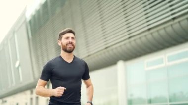 Beyaz sakallı, mutlu bir koşucu şehir parkının arka planında koşuyor. Sabah koşusu. Aktif sağlıklı yaşam tarzı uygunluğu. Dışarıda spor antrenmanı. Sporcu eğitim koşusu egzersizi