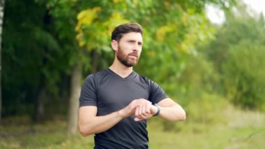 Modern hipodrom koşucusunda akıllı görünümlü beyaz bir adam. Akıllı spor bilekliği kullanıyor. Portre formalı erkek sporcu.