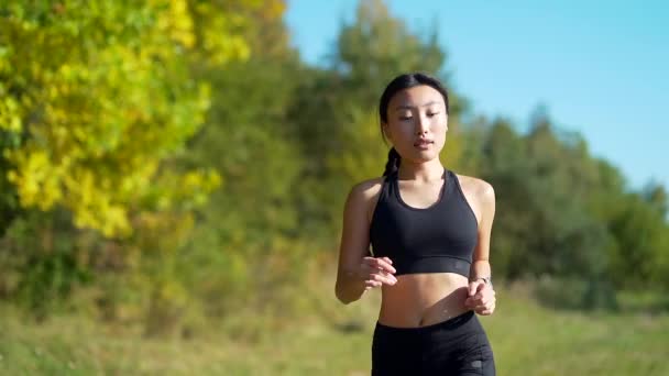 年轻的亚裔快乐女性跑步者在森林或城市公园里慢跑 早上慢跑 积极健康的生活方式 迷人的健身女性 户外运动 在新鲜空气中进行田径训练 — 图库视频影像