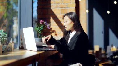 Genç bayan serbest çalışan ya da online çalışan ya da bir kafede okuyan bir öğrenci. Takım elbiseli Asyalı iş kadını iş yerindeki çalışma masasında dizüstü bilgisayar kullanıyor. Bir deftere yazıyor. Öğren