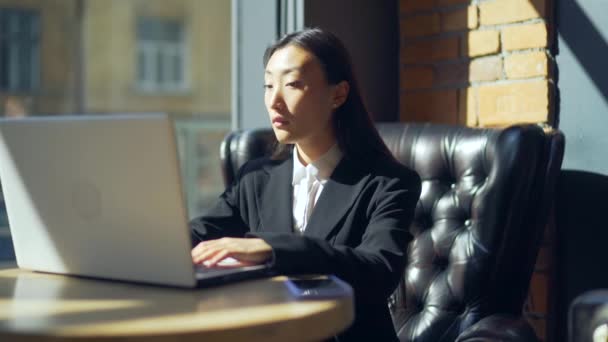 若い女性のフリーランスや学生がオンラインで働くか カフェで遠隔で勉強しています スーツ姿のアジアのビジネス女性は同僚の職場でラップトップを使用しています — ストック動画