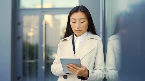 亚洲女商人穿着西服站在外面 手握平板电脑 背景是现代写字楼中心 男的用智能手机 男的用手机 男的用手机 — 图库视频影像