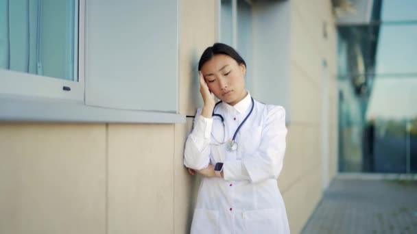 肖像画紧张的亚洲女医生站在医院外 在诊所附近疲惫不堪的沉思的医生 用听诊器进行大流行病医疗擦洗时医护人员的压力 — 图库视频影像