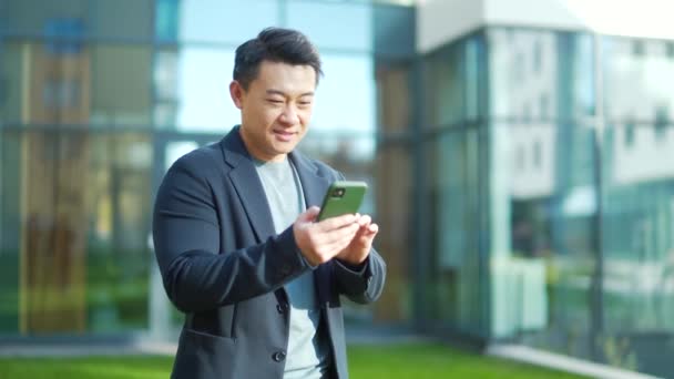 Έξοδος Ασίας Επιχειρηματίας Γιορτάζοντας Επίτευξη Κοιτάζοντας Smartphone Εξωτερική Επιτυχημένος Επιχειρηματίας — Αρχείο Βίντεο