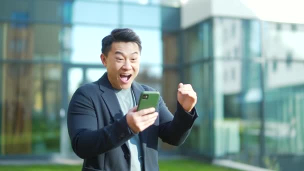 Вышел Азиатский Бизнесмен Празднуя Достижения Глядя Смартфон Открытом Воздухе Успешный — стоковое видео
