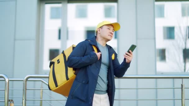Asyalı Erkek Yemek Kuryesi Cep Telefonu Uygulamasını Akıllı Telefondan Kullanırken — Stok video