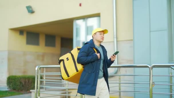 Asiático Mensageiro Comida Masculina Uniforme Amarelo Usando Aplicativo Móvel Smartphone — Vídeo de Stock