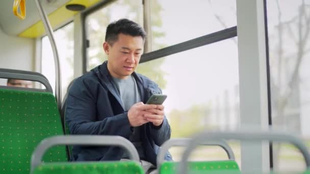 Asijský Muž Jezdí Veřejnou Dopravou Sedí Sedadle Pomocí Mobilního Telefonu — Stock video
