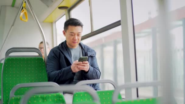 Asijský Muž Jezdí Veřejnou Dopravou Sedí Sedadle Pomocí Mobilního Telefonu — Stock video