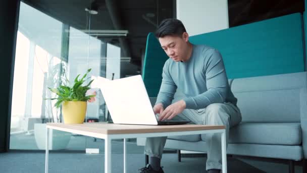 現代のオフィスの同僚センターでラップトップで作業しているアジアの男性フリーランスコンピュータのスマートプロの従業員の創造的 革新的な起業家の共同作業ガラススペースを入力する男学生や教師 — ストック動画