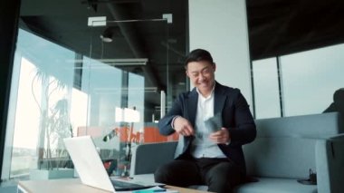 Mutlu Asyalı iş adamı sayımları, dalgalar, atışlar, makama bakan para. Kazanan kameraya bakıyor. Borsa zaferi kutluyor.