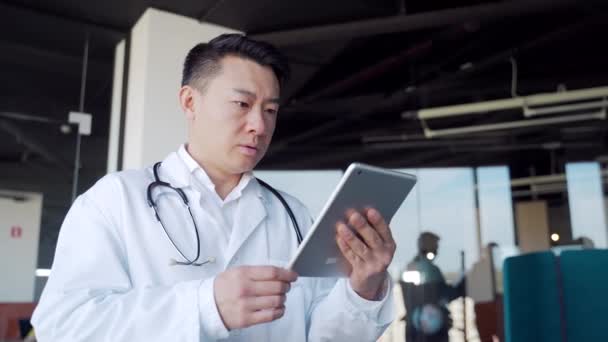 Asian Male Doctor Advise Patient Remotely Using Digital Tablet Communicates — Vídeo de Stock