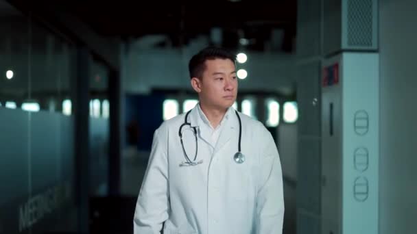 Asian Male Doctor Walks Hallway Modern Hospital Clinic Portrait Serious — Stockvideo