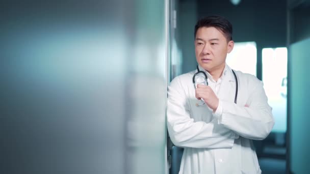 亚洲医生站在医院的室内 神气活现 试图用听诊器冲洗病灶时医护人员的疲劳沉思的临床 伤病员压力 — 图库视频影像