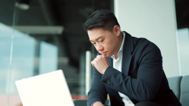 在现代写字台上的笔记本电脑上工作的亚洲商人 自信而专注的男人穿着正式的西服在室内 思考如何用灵感来解决问题 启动阶段 — 图库视频影像